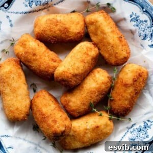 A close-up cropped image of golden-brown chicken croquettes presented invitingly in a blue and white patterned bowl, highlighting their crispy texture.