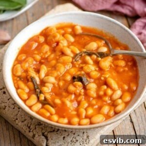 A bowl of tomato beans in a bowl with sage leaves, representing the Fagioli all'uccelletto dish.