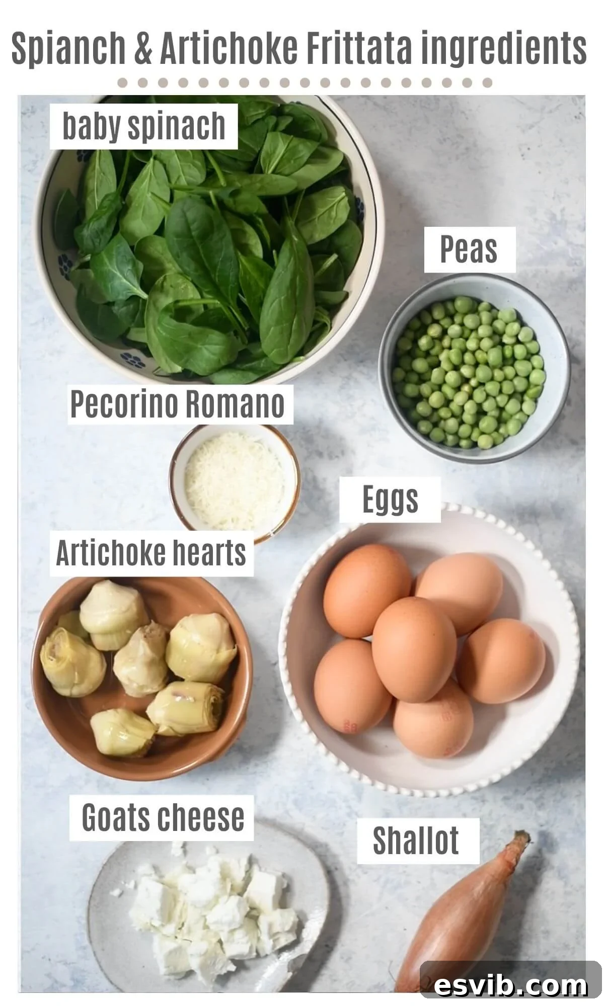An overhead shot of all the fresh ingredients laid out, including eggs, spinach, artichokes, peas, shallots, and goat cheese, ready for a spinach and artichoke frittata.