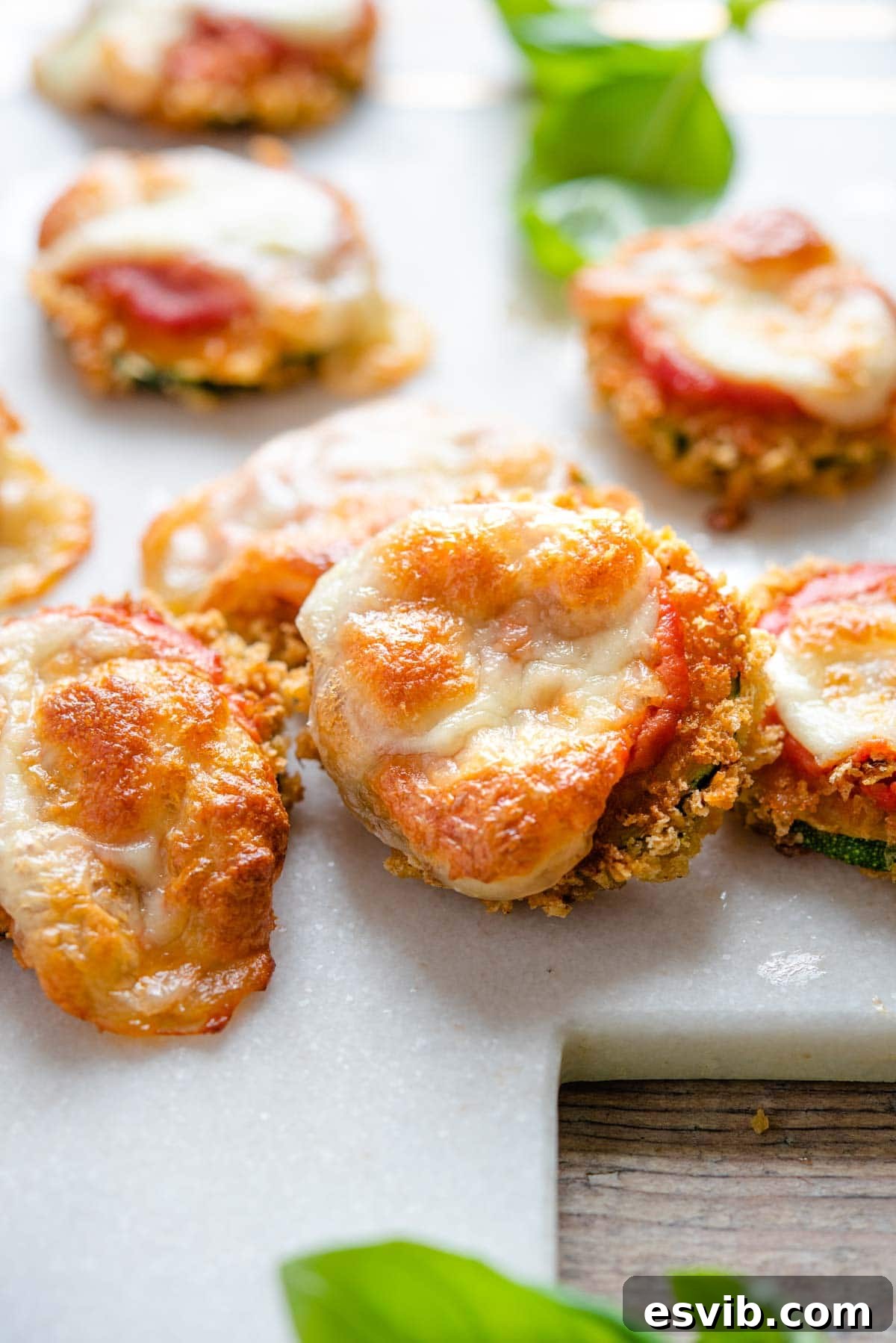 A close-up shot of a single, perfectly golden-fried zucchini pizza bite, highlighting the melted mozzarella and rich tomato sauce, ready to be enjoyed.
