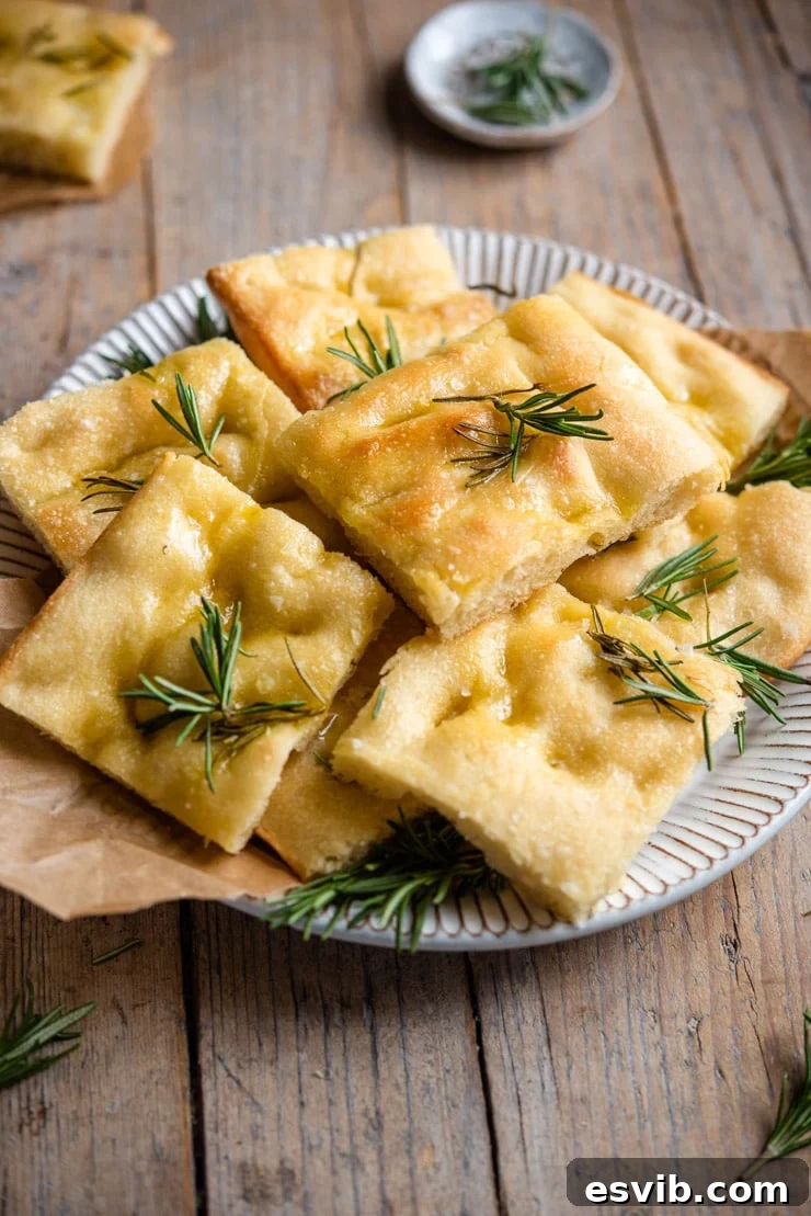 Rosemary Focaccia cut into delicious squares. A side shot of freshly baked rosemary focaccia, cut into squares, on a rustic plate, ready to be served.