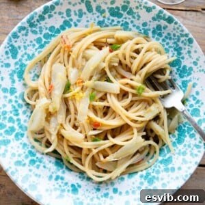 A cropped square image of roasted fennel pasta in a blue bowl, garnished with fennel fronds.