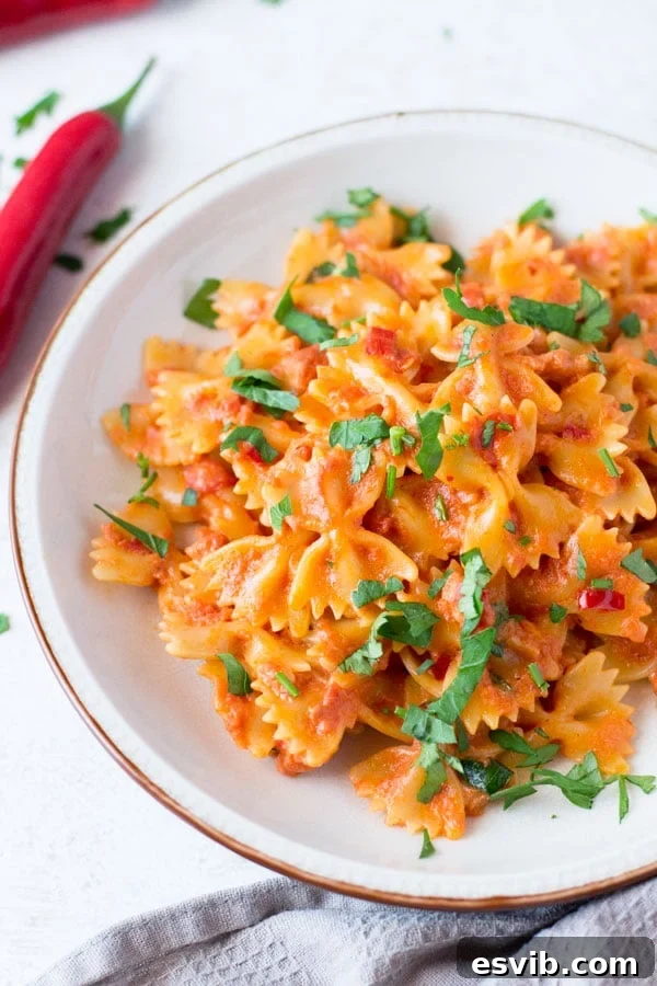 A delicious and simple farfalle pasta with pancetta recipe with fresh chili, garlic and a dash of cream. This simple pasta dish makes a great quick weeknight meal that's delicious eaten hot or cold. Italian pasta recipes inside the rustic kitchen Close-up of farfalle pasta being tossed with a creamy tomato and pancetta sauce, garnished with fresh parsley.