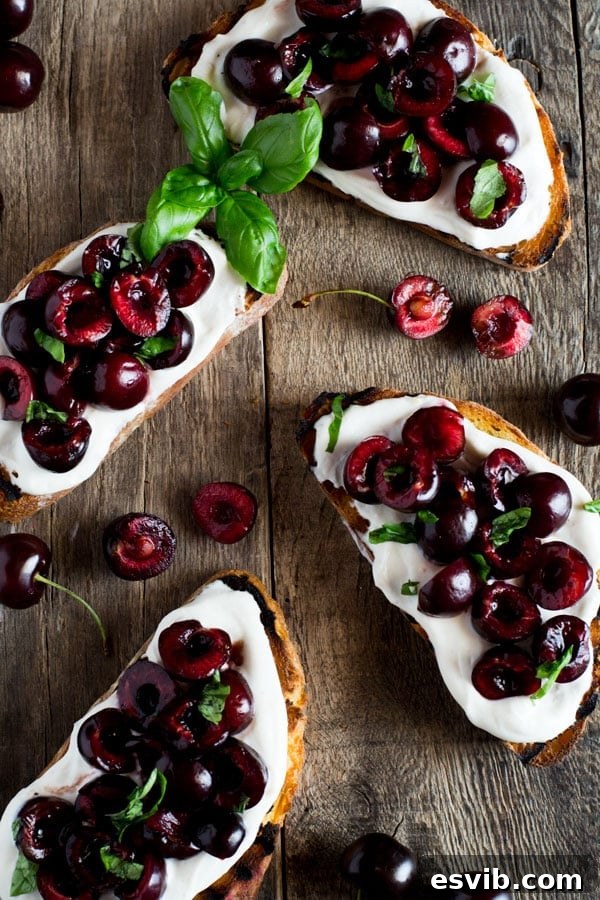 Balsamic-Kissed Cherry Ricotta Toast 2 Whipped ricotta toast with vibrant red balsamic cherries and fresh basil leaves, showcasing a perfect appetizer on a rustic wooden board.