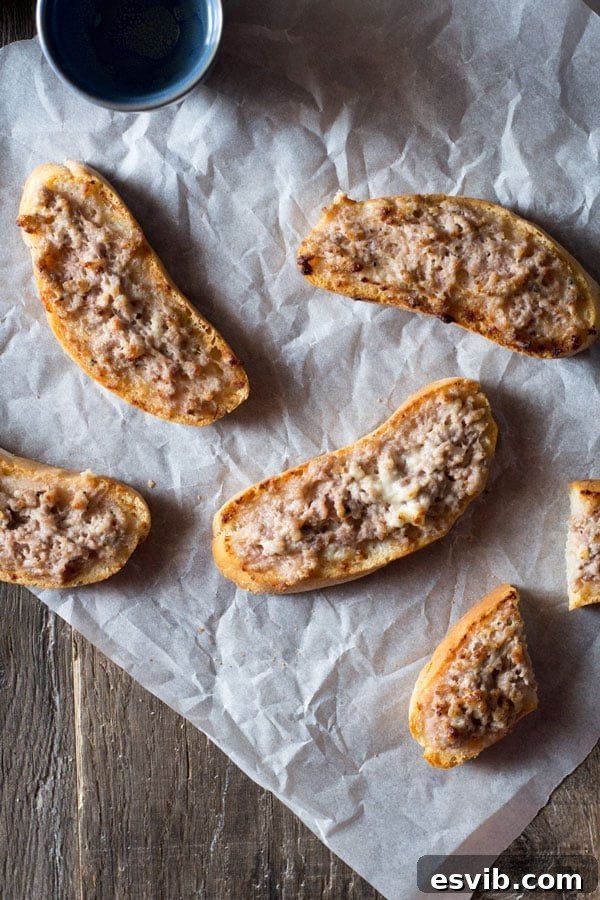 Three Stracchino and Italian Sausage Crostini baked to perfection on a wooden board