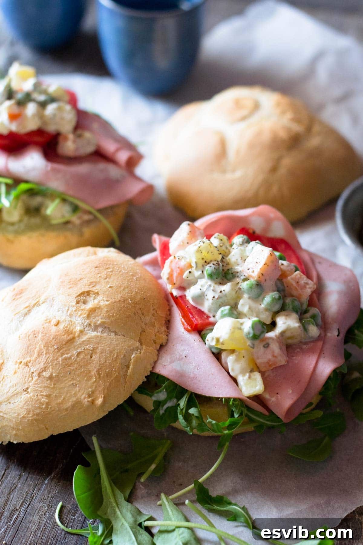 A close-up shot of creamy Russian Salad on a rustic bread roll, ready to be eaten.