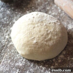 A ball of yeast-free pizza dough on a wooden surface, ready for preparation.
