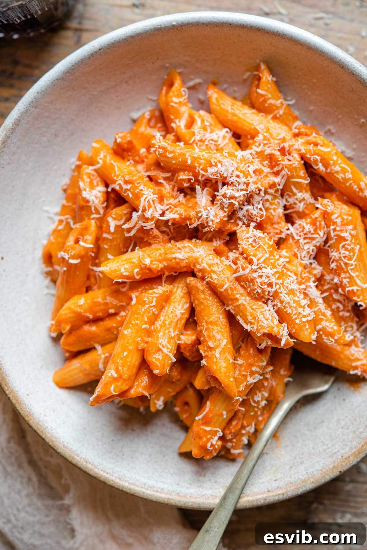 A close up of penne alla vodka in a rustic bowl, garnished with fresh herbs, ready to be served
