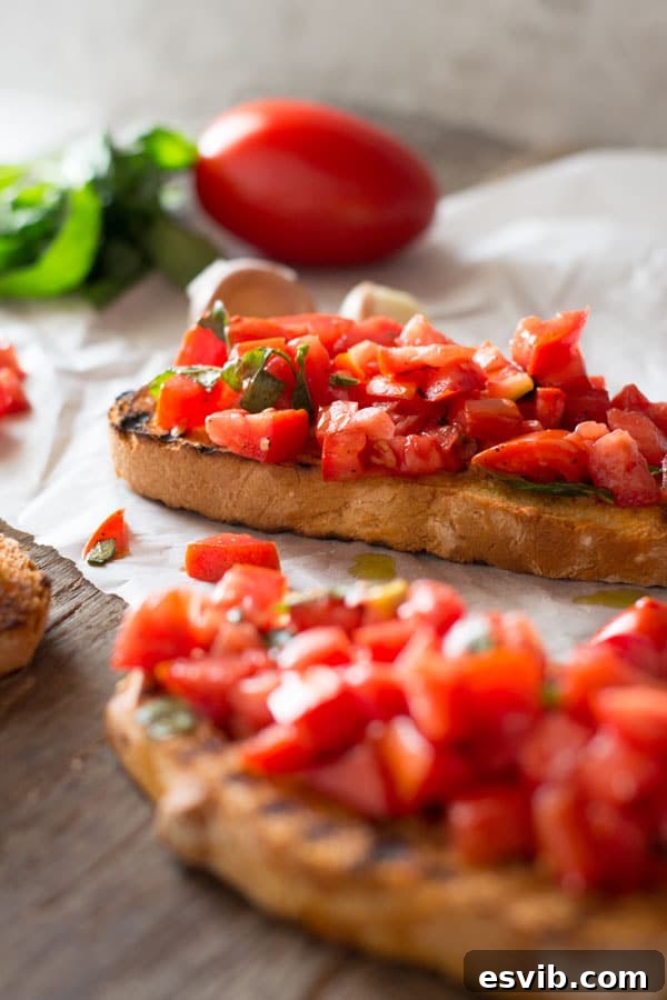 A close-up view of generously piled, vibrant chopped fresh tomatoes and fragrant basil on crispy, golden-brown garlic toast, showcased on a rustic wooden cutting board.