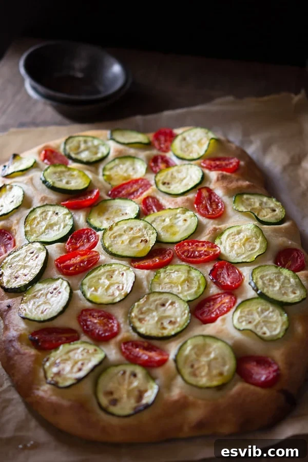 Delicious zucchini tomato focaccia. A simple Italian snack or appetizer with a crispy crust and soft, light and fluffy middle. Authentic Italian recipes and traditional Italian recipes at Inside the rustic kitchen. Zucchini and tomato focaccia is a delicious Italian snack, appetizer or side dish. Made with a soft, light and fluffy dough and topped with fresh summer vegetables at Inside the rustic kitchen.