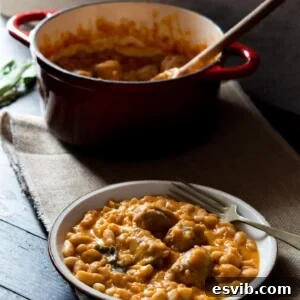 Tuscan bean stew with sausages on a plate, fork at the side and pot in the background