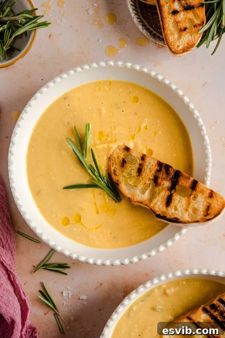 Overhead shot of a bowl of Tuscan Chickpea Soup, garnished with a sprig of fresh rosemary and a drizzle of olive oil