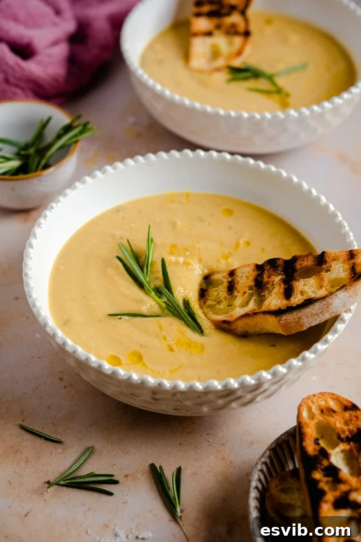 A side view of a bowl of creamy Tuscan Chickpea Soup, served with a piece of crusty bread, perfect for dipping