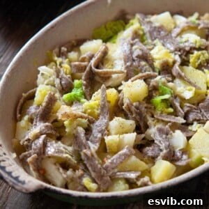 A close up of pizzoccheri pasta in a baking dish with potatoes and cabbage