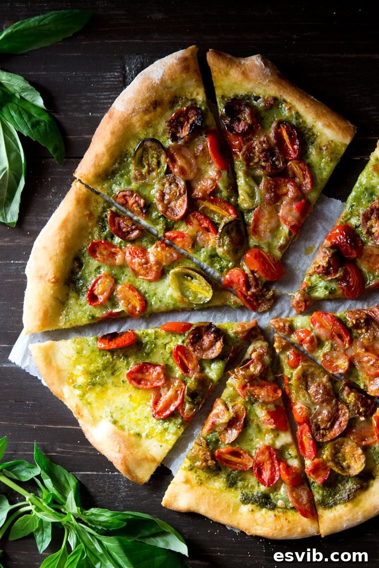 Delicious basil pesto pizza slices on a wooden board, topped with cherry tomatoes and mozzarella, garnished with fresh basil leaves.
