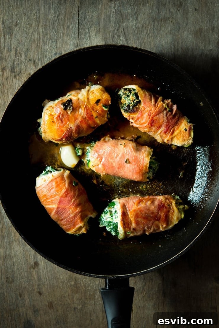 Prosciutto Chicken Involtini with Spinach and Ricotta in Red Wine Sauce Overhead photo of golden-brown chicken involtini in a pan, garnished with a clove of garlic and a luscious red wine sauce