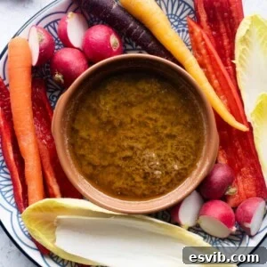 Bagna Cauda, a warm Italian garlic and anchovy dip, served in a traditional terracotta dish with an array of colorful raw vegetables surrounding it, ready for dipping and communal enjoyment.