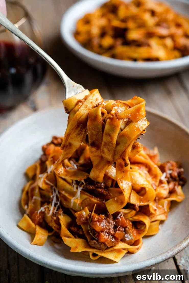 Authentic Italian Beef Ragu: A Timeless Classic 3 A fork picking up some beef ragu and pasta from a bowl, showcasing the rich sauce and tender meat.