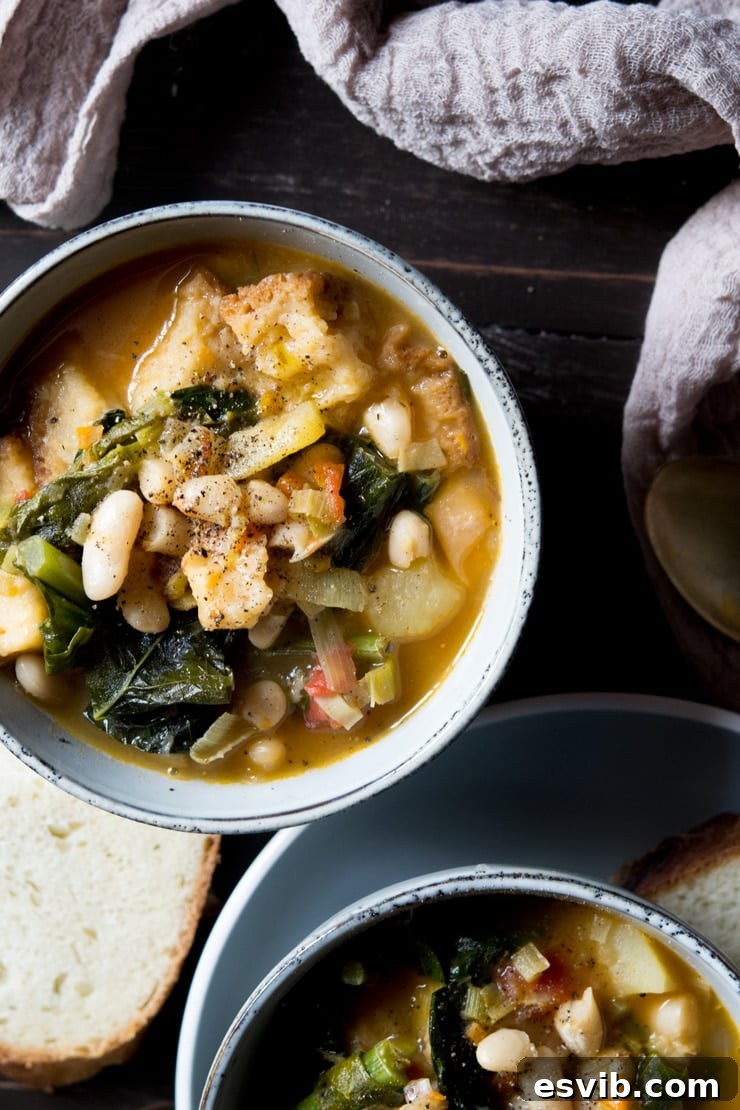 Traditional Ribollita Tuscan Vegetable Stew with Bread An inviting overhead shot of a steaming bowl of traditional Ribollita, a hearty Tuscan vegetable and bread stew, garnished with a swirl of olive oil, with additional rustic crusty bread slices nearby, ready to be enjoyed.
