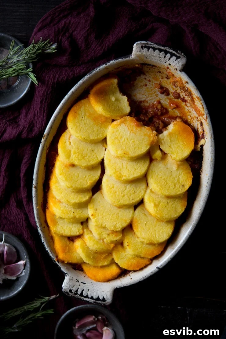 Beef and sausage ragu with baked polenta on top in an oval baking dish Beef and sausage ragu with baked polenta on top in an oval baking dish