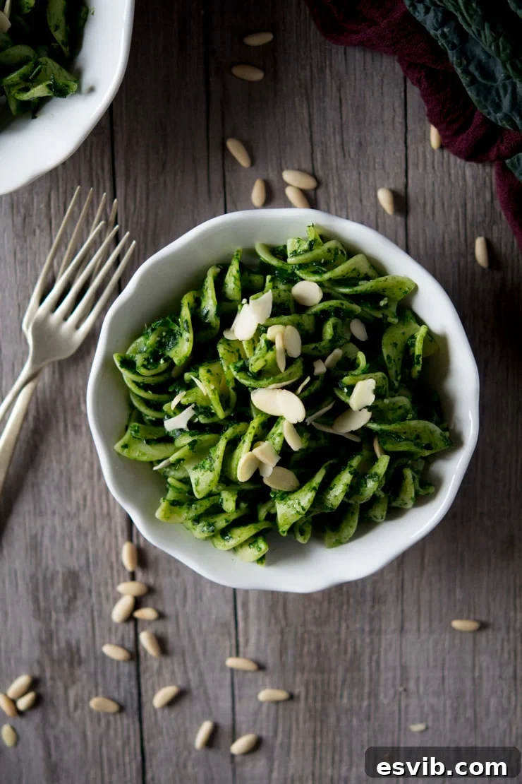 Cavolo Nero Pesto Pasta in a white bowl Vibrant green pesto pasta sauce made with cavolo nero and giant fusilli in a white bowl on a rustic wooden surface, ready to be enjoyed.