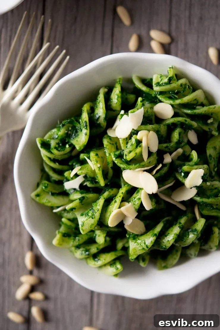 Cavolo Nero Pesto Pasta close up A close-up shot of healthy cavolo nero pesto pasta with giant fusilli, garnished with flaked almonds in a white bowl, ready to eat.