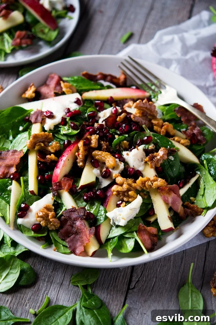 A beautifully arranged winter salad served on a large plate atop a rustic wooden surface, highlighting its vibrant ingredients.