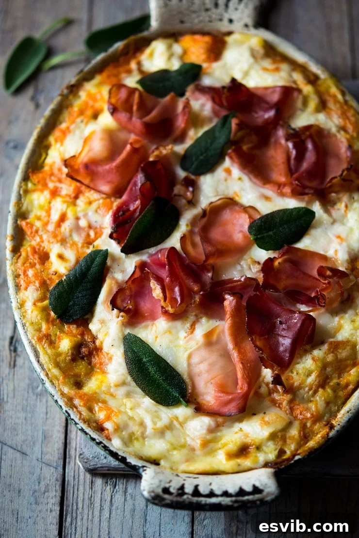 A close-up shot of a creamy butternut squash lasagna with visible layers of pasta, cheese, and squash, garnished with crispy sage.