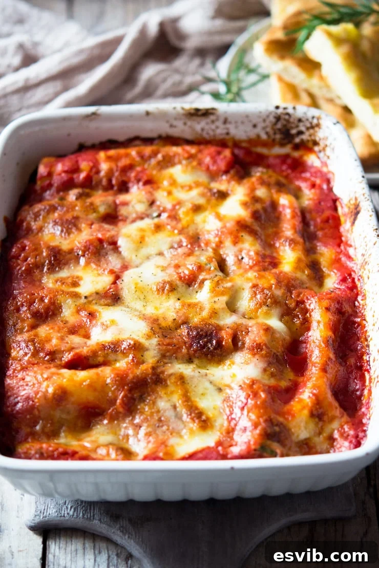 A close up of spinach and ricotta cannelloni in a large baking tray topped with melted mozzarella cheese, ready to be served.
