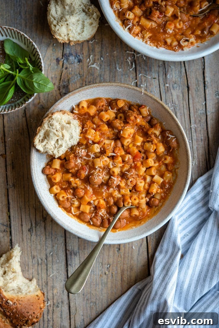An overhead shot of pasta fagioli soup in two bowls with crusty bread