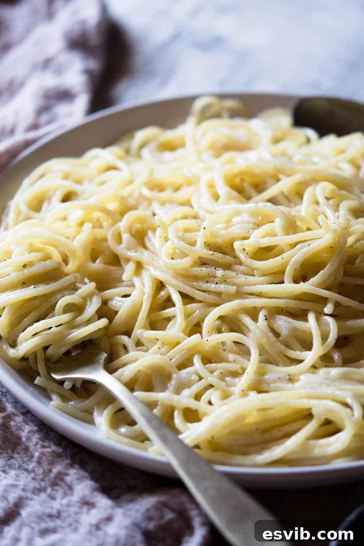 A side shot of a cacio e pepe recipe on a plate with a fork, showing the creamy texture