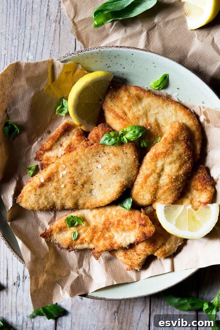 An overhead shot of a batch of golden-brown breaded chicken cutlets, freshly fried and resting on brown parchment paper, ready to be served or enjoyed.