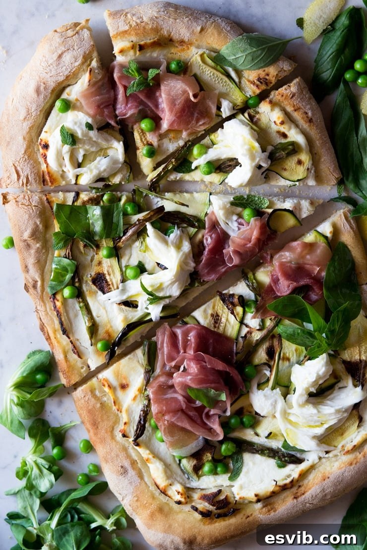 An overhead shot of a white base pizza with zucchini, prosciutto and asparagus An overhead shot of a white base pizza with zucchini, prosciutto and asparagus