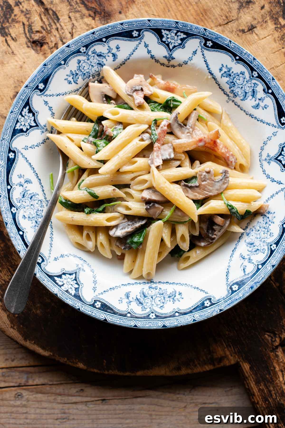 Crispy Guanciale, Mushroom & Spinach Pasta 2 An overhead shot of mushroom spinach pasta in a blue and white bowl.