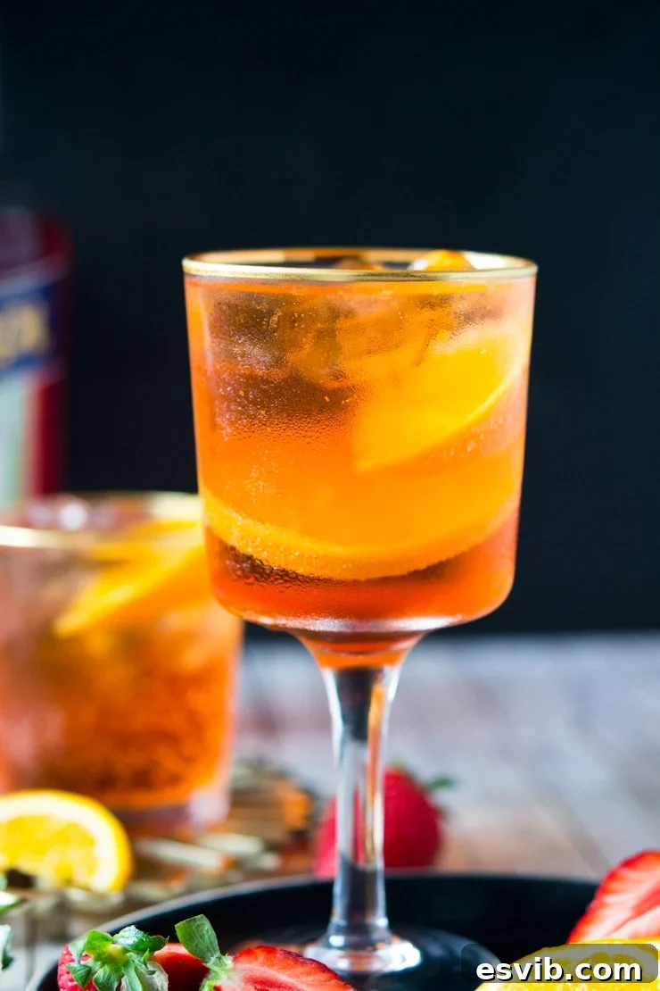 A close up of an Aperol spritz cocktail in a glass with strawberries and slices of orange at the side A close up of an Aperol spritz cocktail in a glass with strawberries and slices of orange at the side
