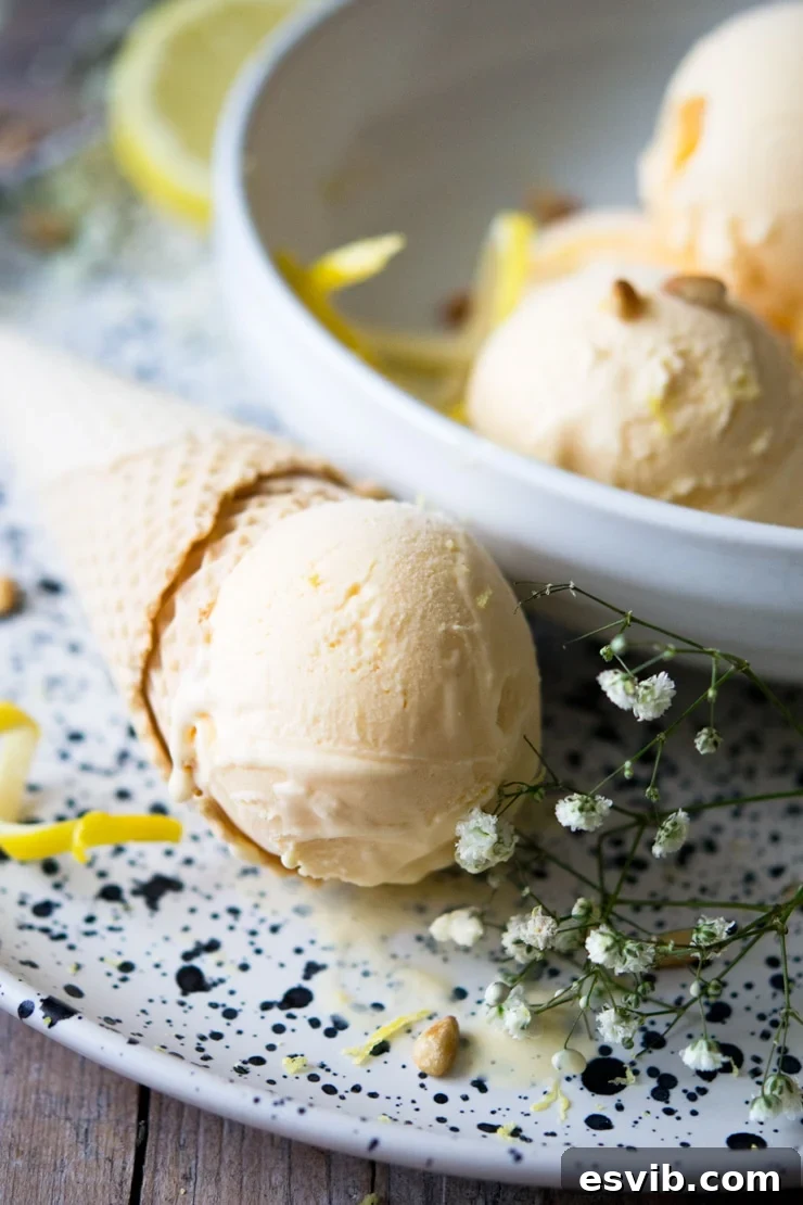A close-up shot of a scoop of creamy lemon ice cream perfectly balanced on a crispy ice cream cone.