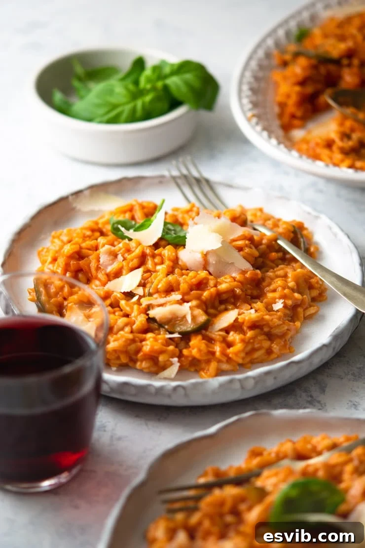 Tomato Risotto with Wine Pairing A beautifully presented plate of creamy tomato risotto with a sprig of fresh basil, a fork, and a glass of red wine in the background, suggesting a delightful meal.