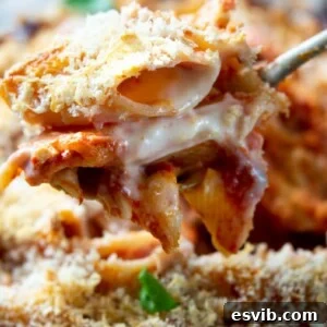 A close up of cheesy tomato baked pasta on a serving spoon.