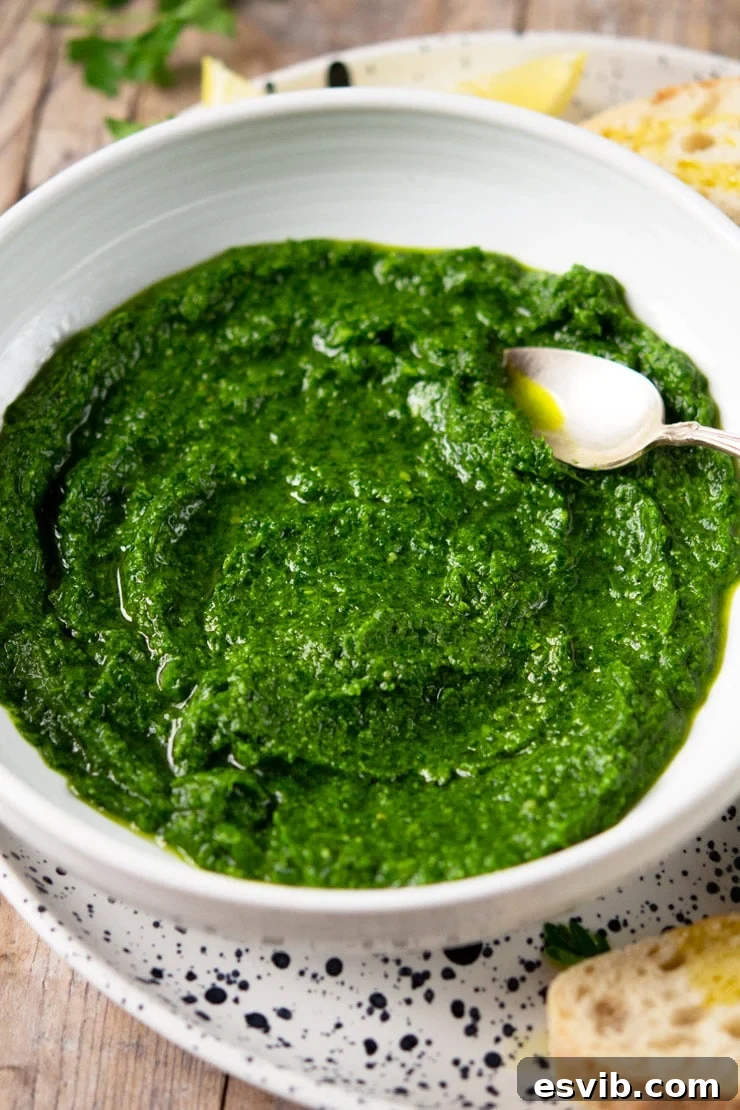 A close-up view of fresh parsley pesto in a white bowl, showing its texture and rich green color.