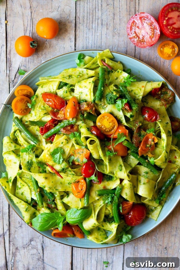 An overhead shot of Pappardelle pasta with green beans, tomatoes, and parsley pesto, ready to serve