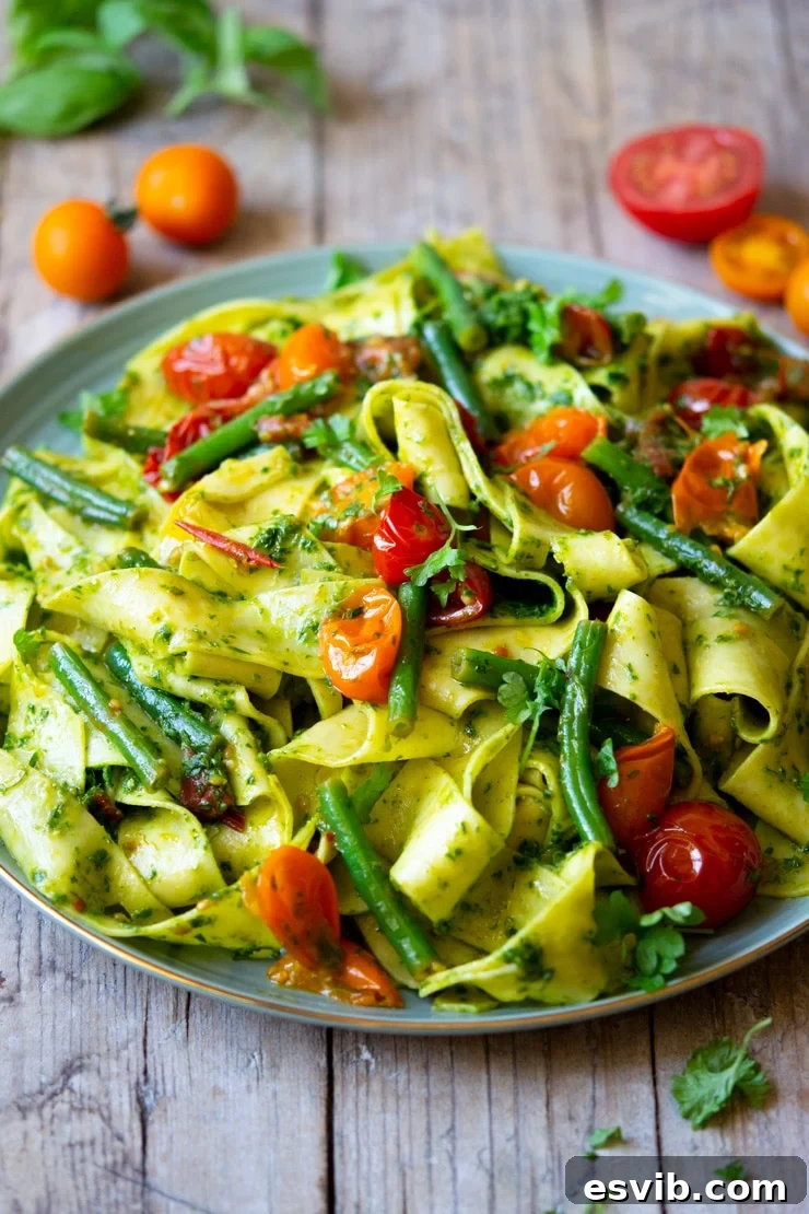 A side view of the finished Pappardelle pasta with green beans, tomatoes, and parsley pesto, showcasing its vibrant colors and rich texture