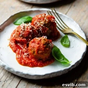 Italian meatballs on a rustic plate with tomato sauce and basil