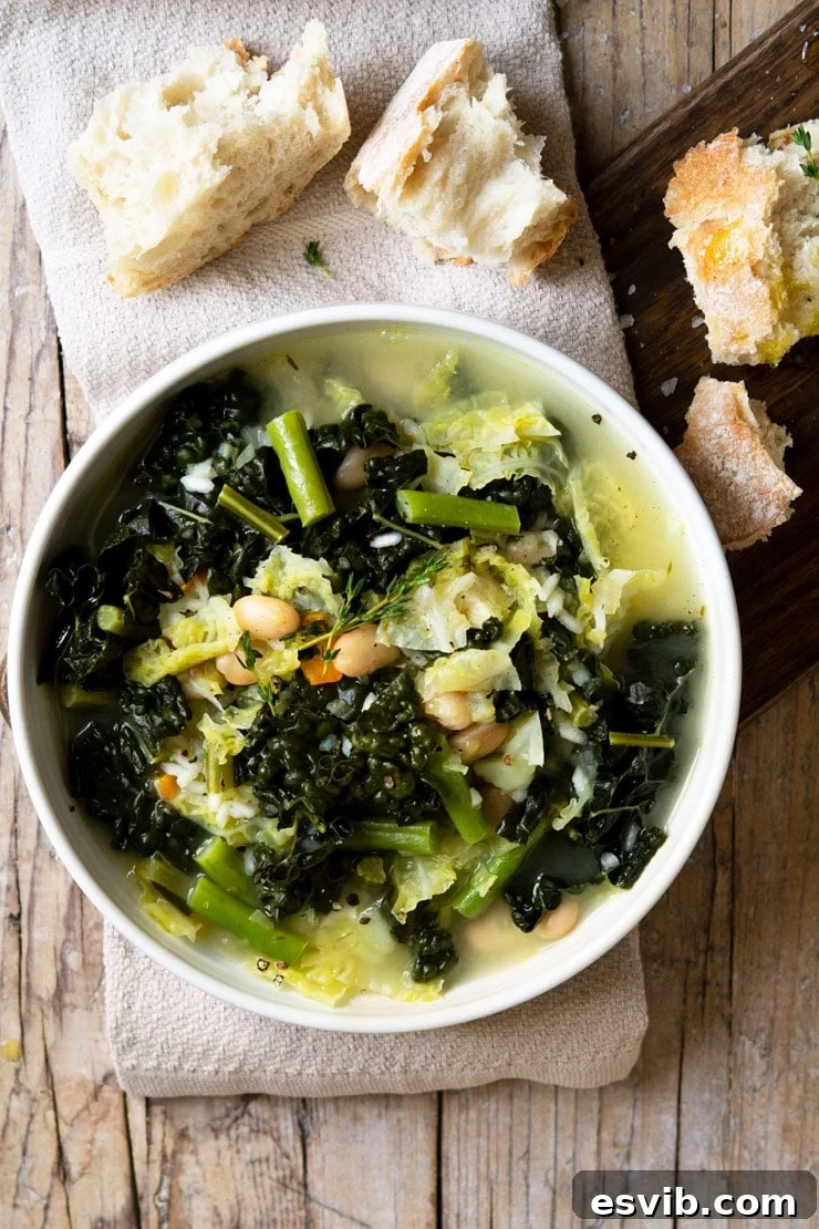 An appetizing overhead shot of a steaming bowl of Tuscan minestrone soup, featuring lush green vegetables and rice, presented on a wooden table.