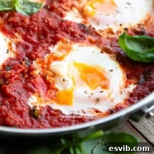 A close up of a perfectly cooked poached egg in tomato sauce with a runny yolk.