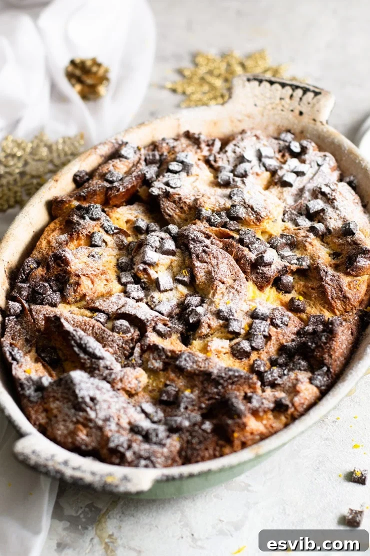 Decadent Panettone Bread Pudding with Melted Chocolate and Powdered Sugar A captivating close-up shot of a rustic oval baking dish generously filled with a rich panettone bread pudding, beautifully topped with shimmering melted chocolate chips and a delicate dusting of powdered sugar, highlighting its indulgent and comforting texture.
