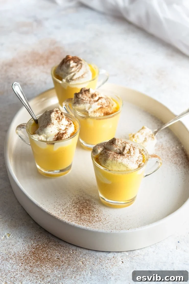 Four glasses of Bombardino drinks on a white plate with whipped cream and cinnamon