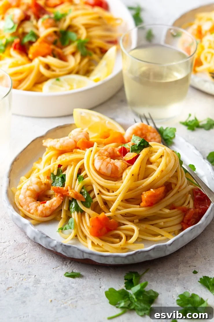 A detailed close-up of the finished shrimp linguine, showcasing the perfectly coated linguine strands, plump pink shrimp, soft burst cherry tomatoes, and scattered fresh parsley, highlighting the dish's vibrant and appetizing appeal.