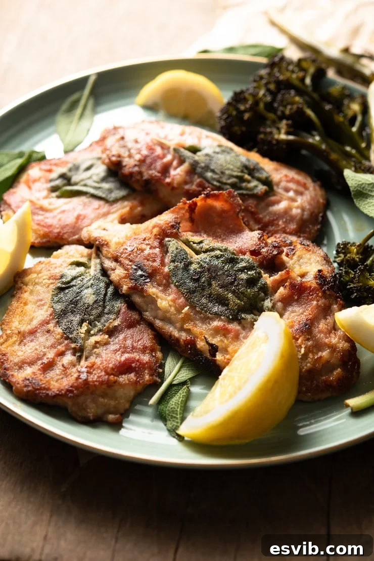 A beautifully plated side shot of Veal Saltimbocca, with its golden-brown veal, crispy prosciutto, and fresh sage leaves, served alongside bright lemon wedges.