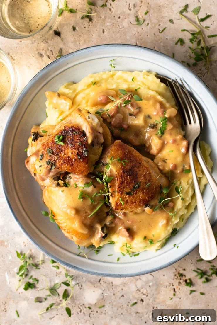 A close-up side view of creamy Tuscan chicken artfully arranged in a blue bowl, accompanied by a generous portion of mashed potatoes, emphasizing the rich texture and appealing presentation of the meal.