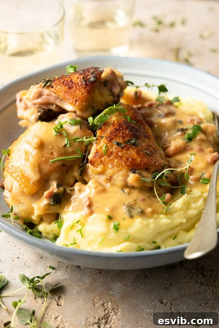 A side profile shot of the rich, creamy Tuscan chicken served in a blue bowl, accompanied by a fluffy portion of mashed potatoes, highlighting the inviting textures and appetizing presentation of the meal.